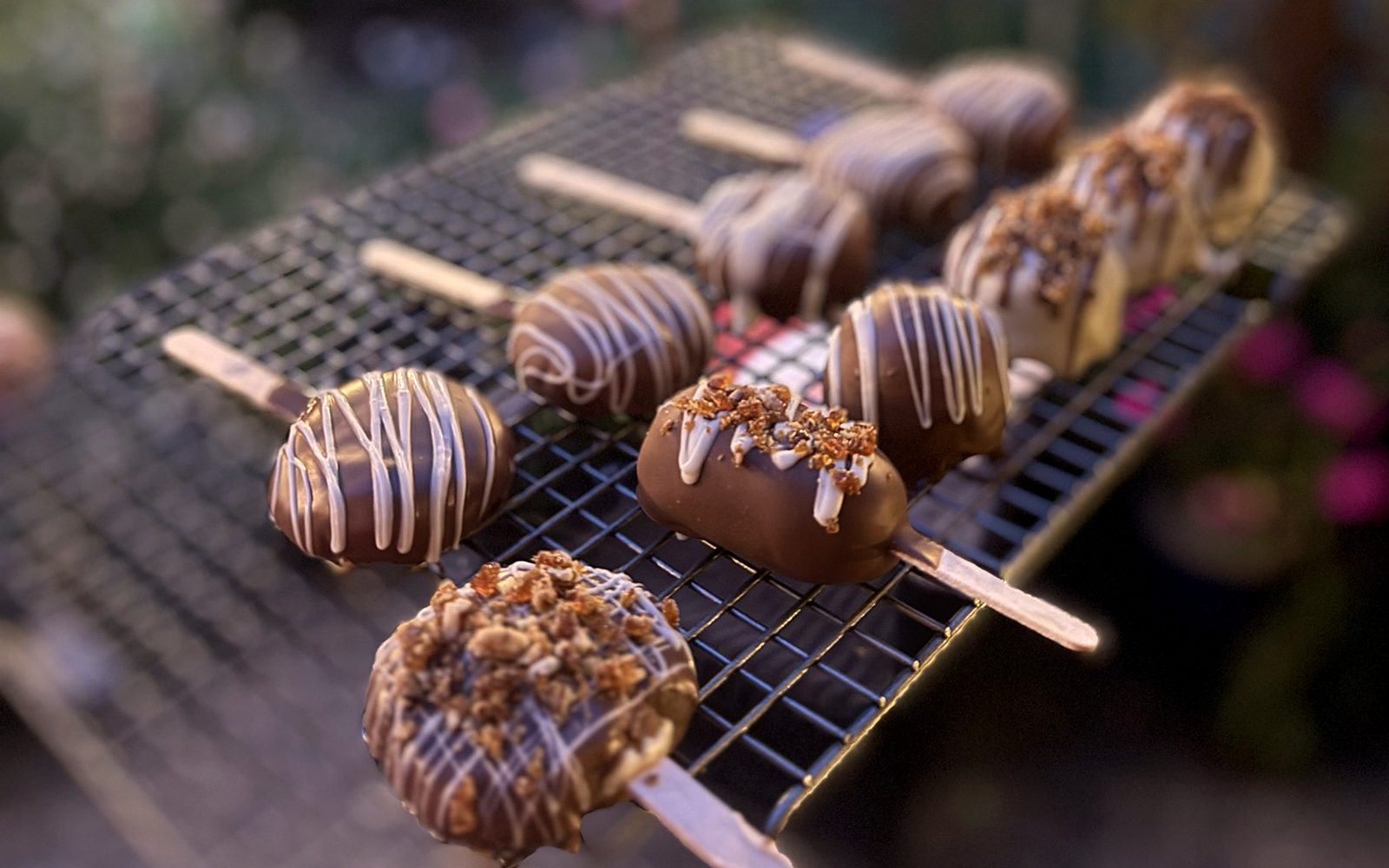 Luce chocolate cake pops with white drizzle and toffee crumble, cooling in the garden at dusk